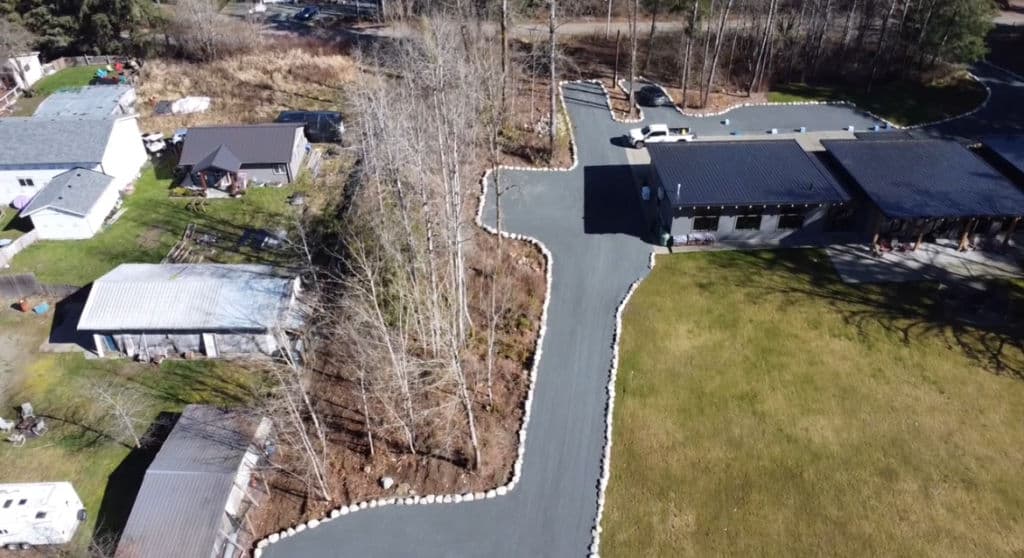 Aerial view of a modern building with landscaped driveway and surrounding trees.