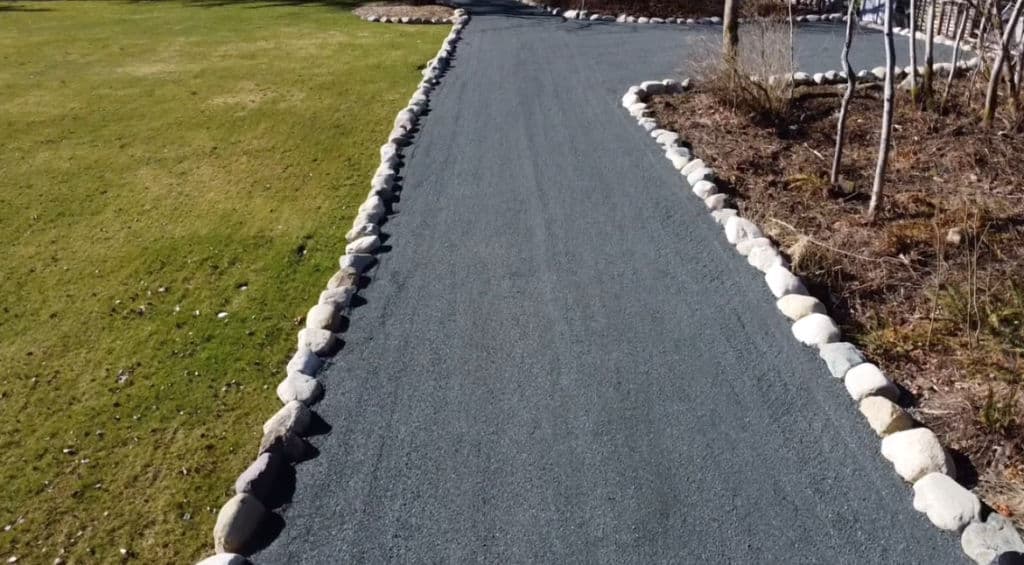 Gravel pathway bordered by stones in a landscaped garden setting.