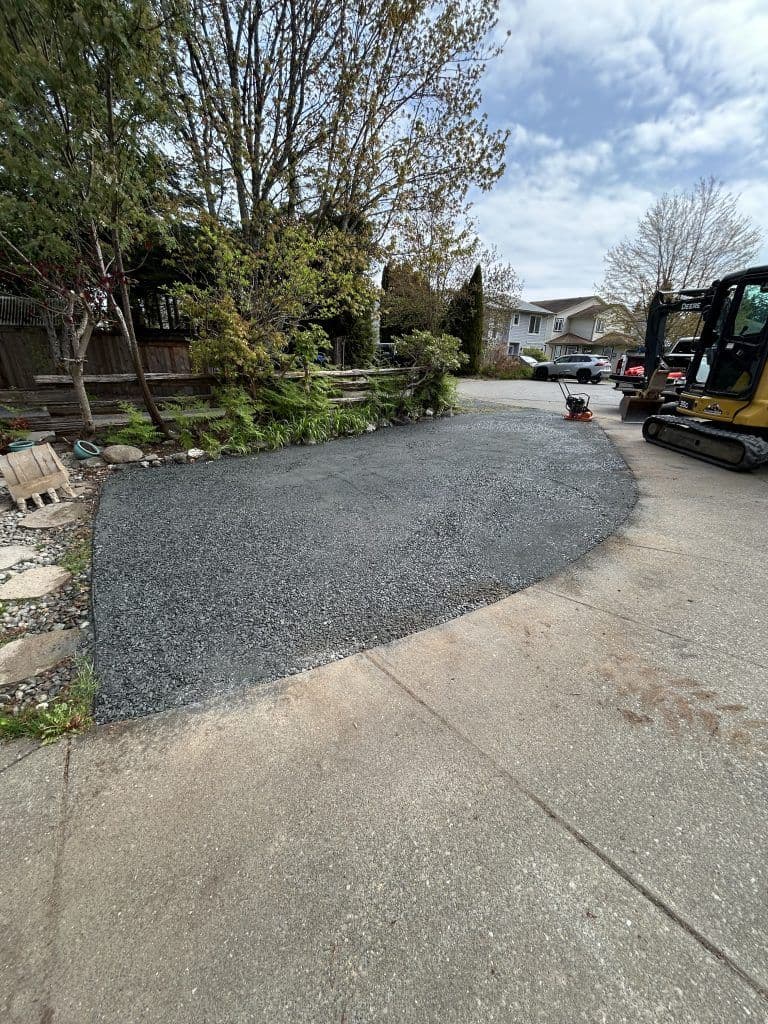 Freshly laid gravel driveway with surrounding greenery and construction equipment.