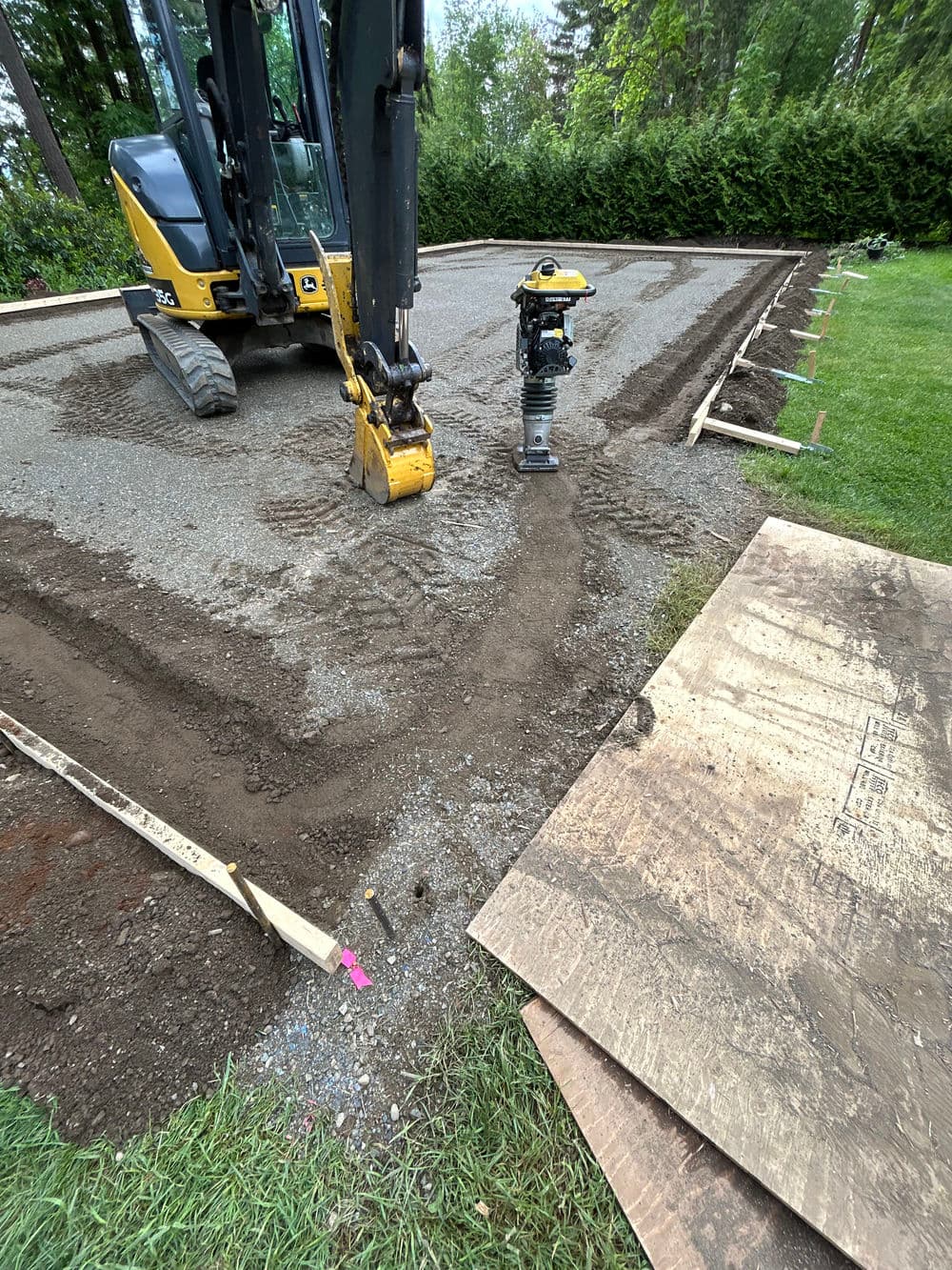 Excavation site with machinery, gravel, and construction materials for landscaping preparation.