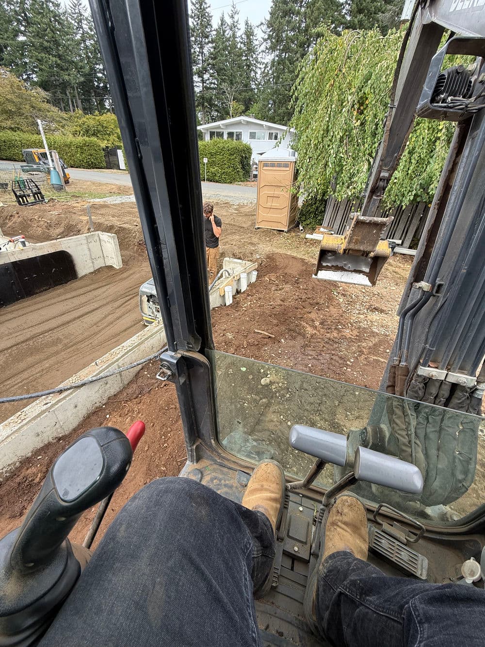 Operator's view from excavator cab, showcasing construction site and equipment in action.