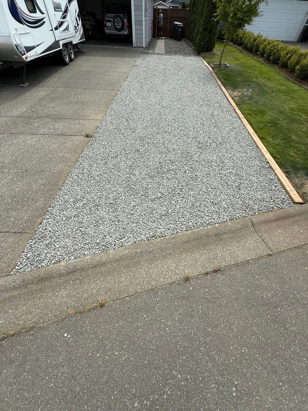 Gravel driveway extension with bordered grass on the side and RV parking in the background.