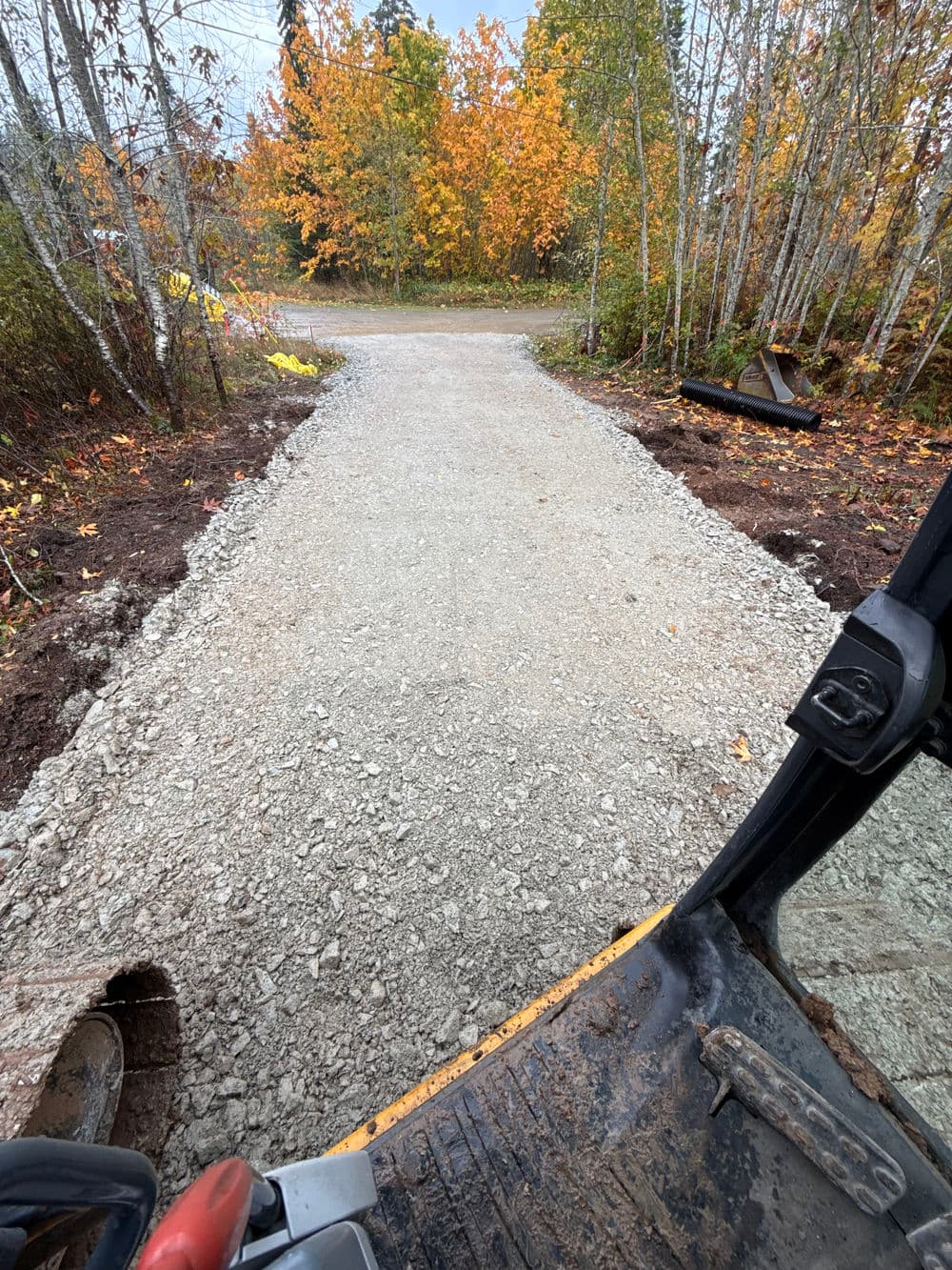 Gravel pathway under construction with autumn foliage in the background.