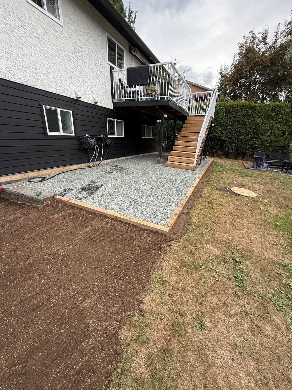 patio area under a deck with gravel surface, stairs, and landscaping in progress