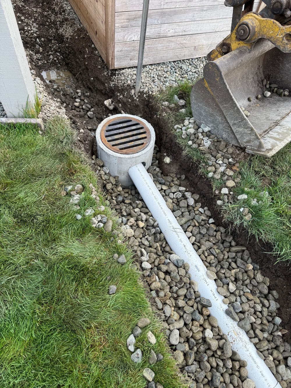 Drainage system installation with a trench, rocks, and equipment for effective water management.